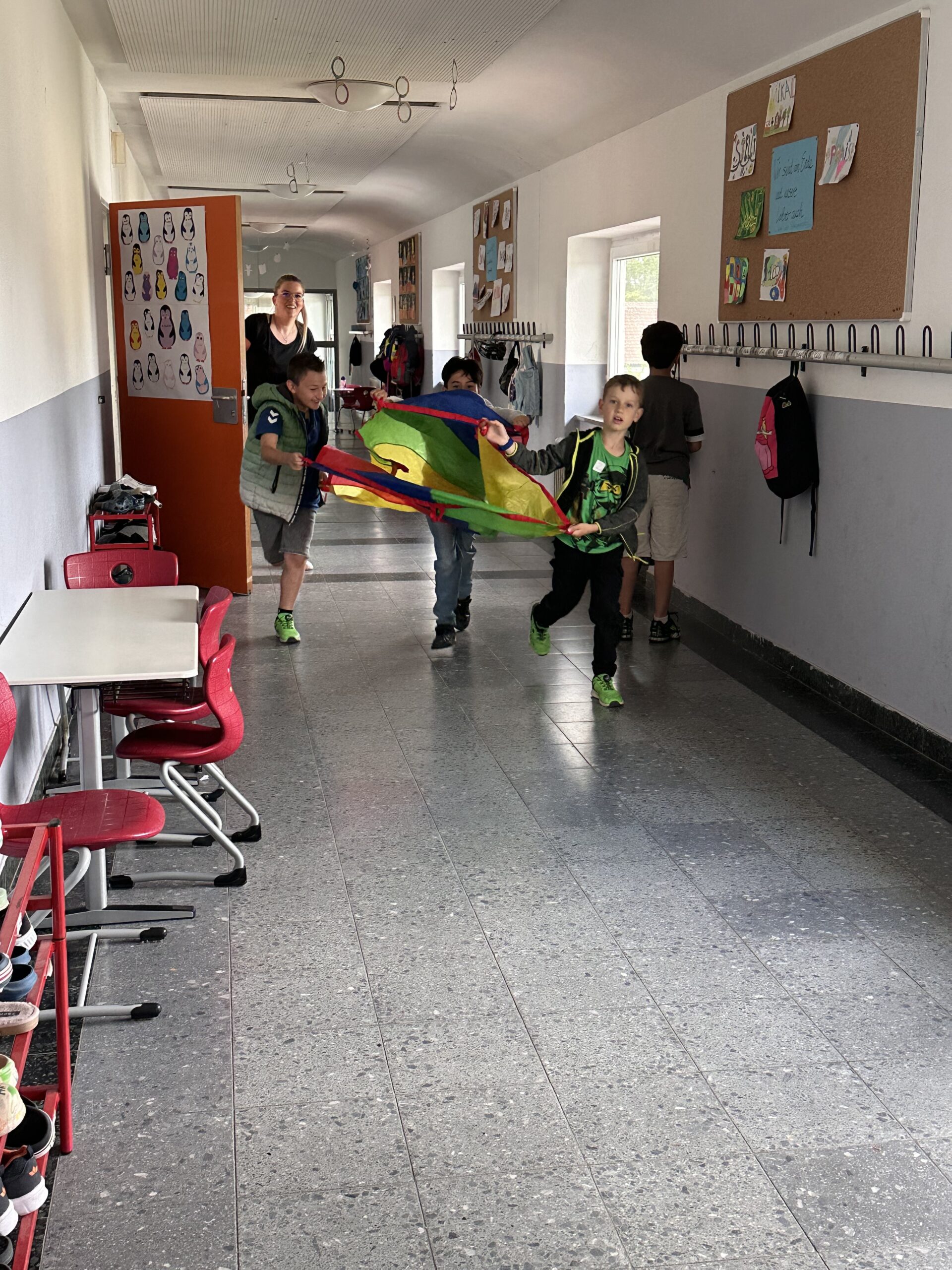 Kinder rennen mit Plane über den Flur